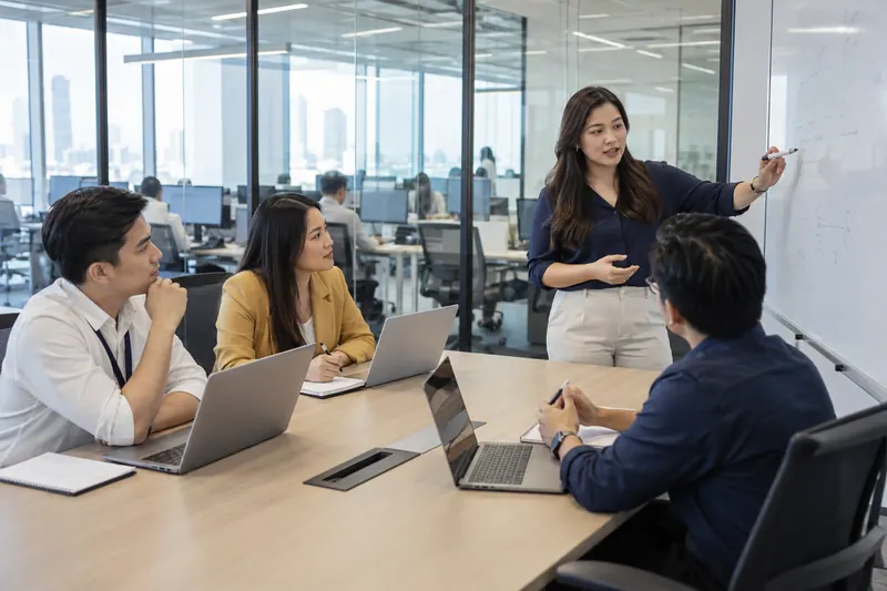 Illustrative scene of a team meeting in a glass-walled office conference room.